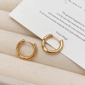 Detailed view of gold hoop earrings with three inlaid zircons on a jewelry tray - Gold