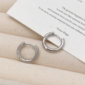 Detailopname van zilveren oorringen met drie ingelegde zirkonia op een linnen standaard - Zilver