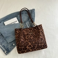 Bolso tote de leopardo con asas de cuero marrón y cadena dorada sobre chaqueta vaquera - Marrón