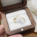 Primer plano de anillo de camelia dorada con circonita en estuche de terciopelo - Dorado