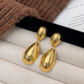 Schicke goldene Wassertropfen-Ohrringe mit poliertem Spiegel-Finish vor Kulisse - Gold