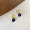 Nahaufnahme der Vintage-Goldohrringe mit quadratischen schwarzen Edelsteinanhängern - Schwarz