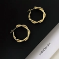 Macro detail of 18K gold plated twisted hoop earrings with a secure clasp design - Gold Spiral Crossover Earrings