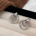 Macro shot of silver triple interlocking geometric circle earrings on beige velvet - Silver