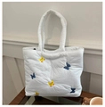 Gros plan sur la broderie papillon et le tissu matelassé du grand sac cabas - Blanc