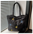 Gros plan de la broderie papillon sur un sac fourre-tout noir matelassé élégant - Noir