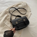 Bolso de hombro negro con hebillas doradas de corazón sobre una chaqueta beige - Negro