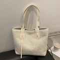 Chic white fuzzy fleece tote bag with cream leather trim on a black sofa background - White