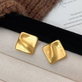 Matte goldene quadratische Ohrstecker mit unregelmäßiger Wellenstruktur auf hellem Stoff - A-1052 Gebürsteter Stil / Gold
