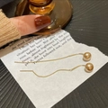 Elegante goldene lange Quastenohrringe mit champagnerfarbenen Perlen auf Buchhintergrund - Gold Lange Quaste Champagner Perle Durchzieher