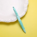 Detalle de portaminas ergonómico verde menta con clip de corazón sobre un plato - Verde fresco