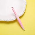 Detalle de portaminas rosa con agarre ergonómico sobre un plato de cerámica blanco - Rosa Adorable
