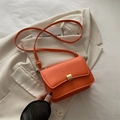 Fashionable bright orange small square bag with gold buckle on a white blazer - Orange