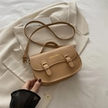 Bolso bandolera pequeño color camello con letras doradas sobre un blazer marfil - Caqui