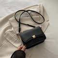 Elegant black minimalist baguette bag with golden buckle on beige blazer jacket - Black