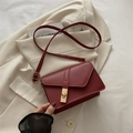 Chic burgundy crossbody bag with geometric flap and golden square lock on cream blazer - Red