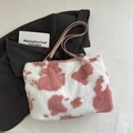 Pink and white cow print plush tote bag with leather handles in flat lay style - Pink