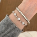 Dettaglio del bracciale a quadrifoglio in argento e dell'anello con diamanti al polso - Set di 2 bracciali e bangle con zirconi argentati