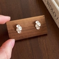Detail shot of matte silver earrings with spiral wave design on a wooden display stand - Small Flower (Silver) / Matte Silver