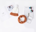 Flat lay of a white and orange knit winter hat with pom-pom and matching neck warmer - Hat and Neck Warmer White Set