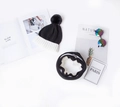 Flat lay of black and white color-block knitted hat and scarf set with pom-pom detail - Hat and Neck Warmer Black Set