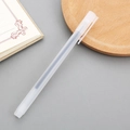 Minimalist frosted translucent white gel pen with visible ink core on a notebook - Matte Transparent With Blue Ink