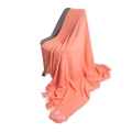 Solid coral pink knitted throw blanket with diamond patterns and tassels on a chair - Watermelon red