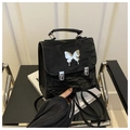 Detail eines schwarzen Mini-Rucksacks mit glänzender Faltenoptik und Schmetterlingsdekor - Schwarz