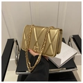 Detalle del acolchado en V dorado y el cierre metálico rectangular del bolso bandolera - Dorado