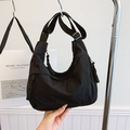 Black crescent dumpling bag made of nylon with woven rope zippers and wide shoulder strap - Black