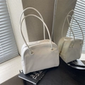 Minimalist white leather tote bag with slim shoulder straps and zipper closure on books - White