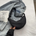 Minimalist black nylon half-moon crossbody bag with adjustable strap on denim background - Black