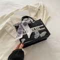 Black tote bag with butterfly embroidery and silk scarf handle accent in a stylish setting - Black