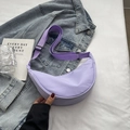 Sac bandoulière demi-lune en nylon lavande avec sangle réglable sur fond denim - Mauve Clair