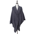 Détail d'un poncho en maille gris foncé avec des franges épaisses sur le bord et le col - Gris