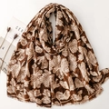 Brown long scarf with beige ginkgo leaf print and frayed edges on white background - Camel