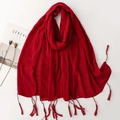 Detail of dark red linen scarf showing lightweight wrinkled texture and fringe tassels - Red