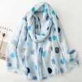Detail of light blue scarf featuring metallic gold polka dots and soft fringe edges - Blue