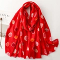 Detail of red scarf with colorful polka dots and artistic frayed edges on white background - Red