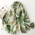 Detailed texture of botanical leaf print on soft satin scarf with gold foil accents - Green