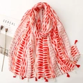 Close-up of red and white geometric wave pattern scarf with stylish tassel details - Red