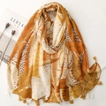 Detail of yellow and orange scarf featuring fringe tassels and abstract leaf patterns - Yellow