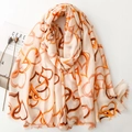 Linen feel scarf with orange heart patterns and soft frayed edges on white backdrop - Orange