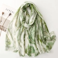 Close-up of green marble print linen scarf with golden stripes and fringe details - Green