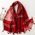 Dettaglio dello scialle paisley rosso con motivi floreali e frange su tavolo bianco - 180*88cm / Rosso