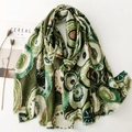 Detailed texture of green cotton-linen scarf with golden geometric prints and frayed edges - Green