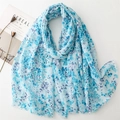 Detail of light blue floral scarf with raw edges beside a lifestyle magazine backdrop - 180x88cm / Blue