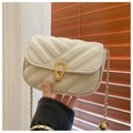 Detail of cream quilted bag with golden horseshoe lock and decorative chain ball - Off White