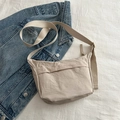 Minimalist beige nylon crossbody bag with wide strap on blue denim background - Khaki
