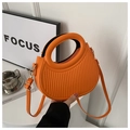 Detail of orange semi-circle handbag featuring vertical striped texture and round handle - Orange